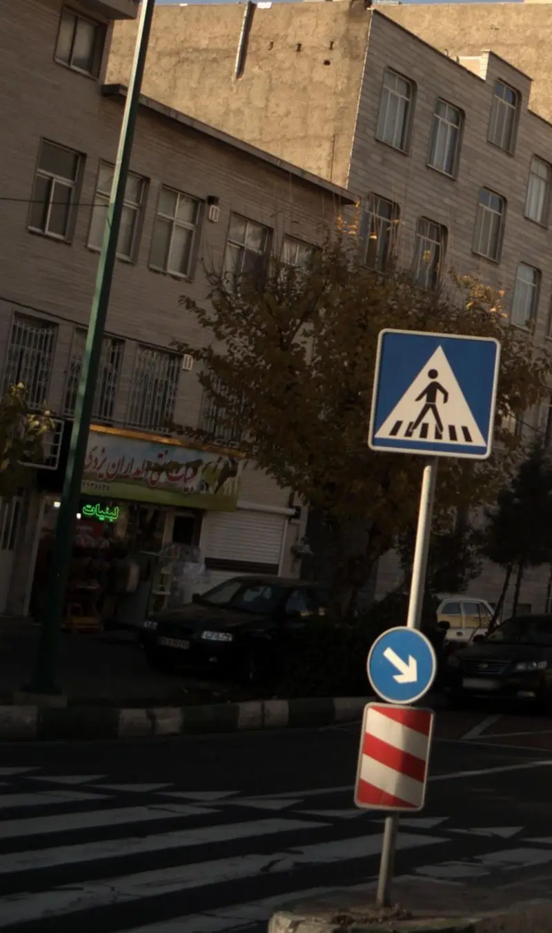 تصویری از نمای بیرونی فروشگاه لبنیات سنتی دامداران یزدی در خیابان، با تابلوی عابر پیاده، خط‌کشی خیابان و چند خودرو.