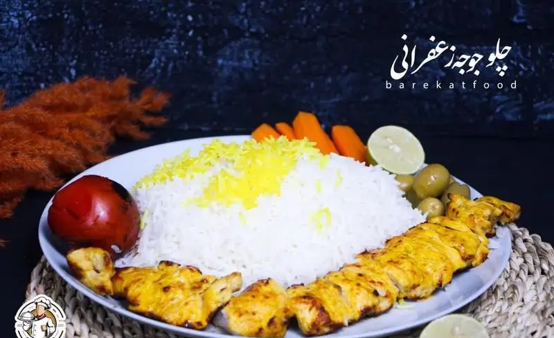 چلو جوجه زعفرانی خوشمزه و اصیل ایرانی از شرکت تهیه غذای برکت، با برنج سفید، گوجه، هویج، زیتون و لیمو تازه سرو شده است.