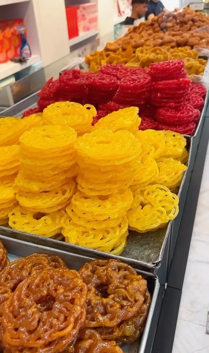 تنوع بی‌نظیر زولبیا و شیرینی‌های رنگارنگ در قنادی سوییت پالاس: دسرهای سنتی زرد، قرمز و قهوه‌ای تازه و خوشمزه.