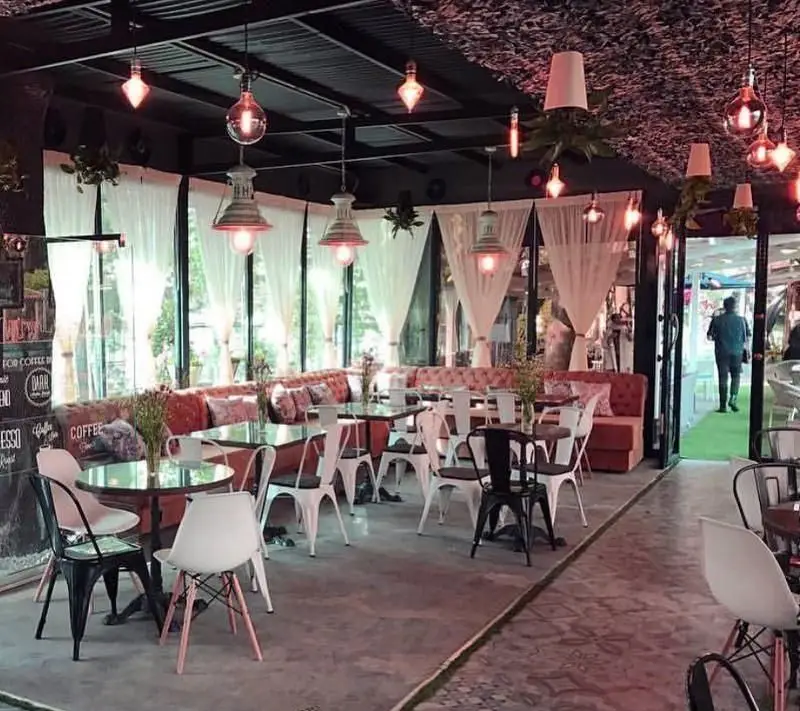 فضای داخلی رستوران فرنگی راگالند با دکوراسیون مدرن و شیک، مبلمان راحتی نارنجی و میز و صندلی‌های متنوع. نورپردازی گرم و پرده‌های سفید زیبایی خاصی به محیط بخشیده است.