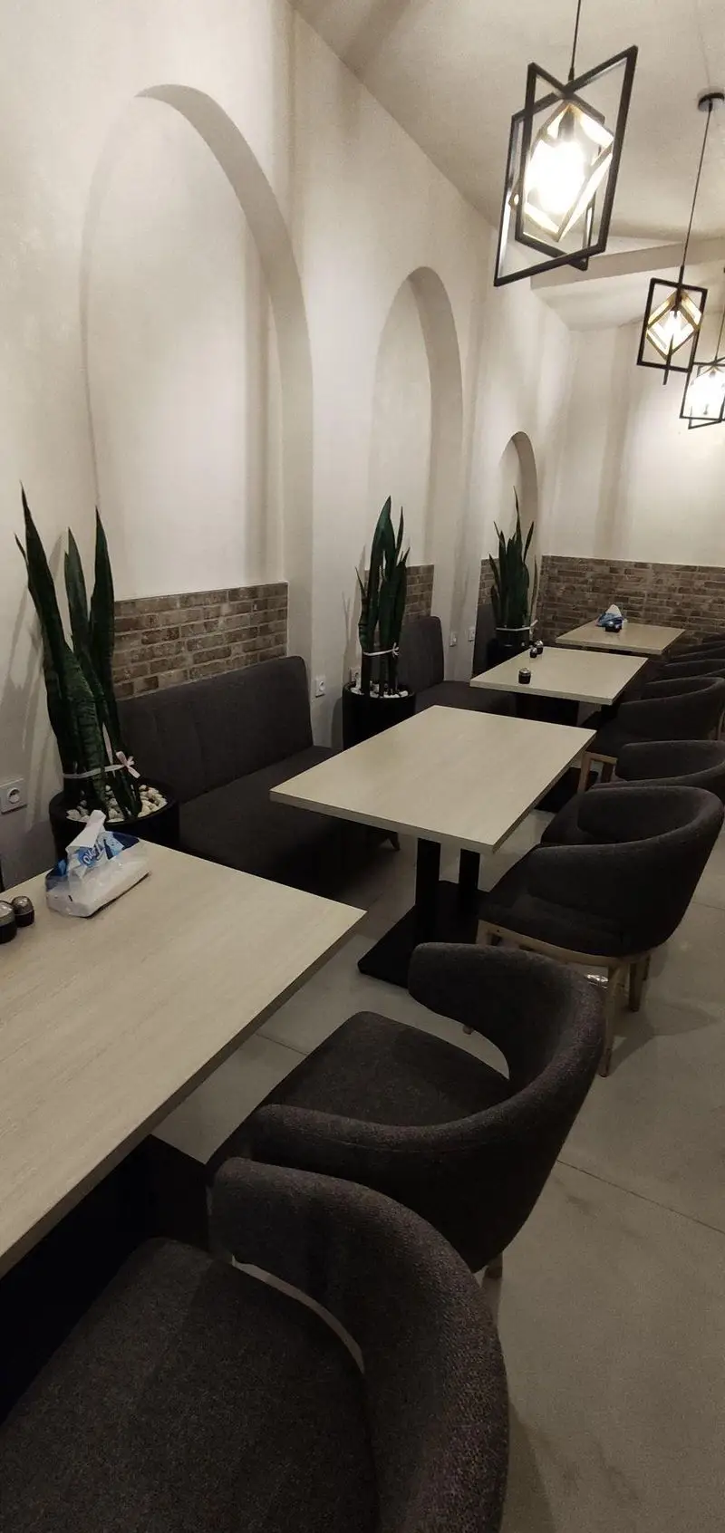 فضای داخلی رستوران سید جلال با دکوراسیون مدرن، میز و صندلی‌های راحت، گیاهان طبیعی و نورپردازی گرم برای تجربه‌ای دلنشین.