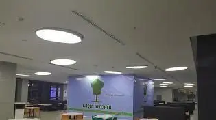 تصویری از فضای داخلی بزرگ و روشن فست فود آشپزخانه سبز، با طراحی مدرن، میز و صندلی‌های راحت و لوگوی سبز درخت در مرکز.