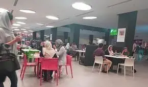 تصویری از مشتریان و فضای داخلی شیک فست فود آشپزخانه سبز، در حال لذت بردن از غذا در محیطی روشن و دوستانه.