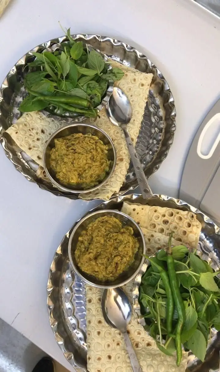 سینیهای غذای اصیل علی جیگری: کاسه خوراک محلی، نان تازه، سبزی خوردن و فلفل سبز، آماده سرو برای تجربهای خوشمزه از غذای ایرانی.
