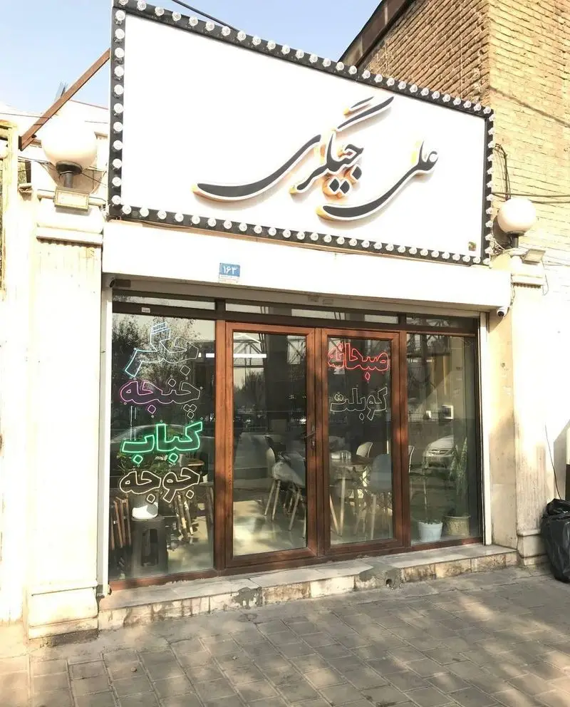 نمای بیرونی رستوران علی جیگری، شامل تابلوی بزرگ با نام "علی جیگری" و ویترین با لیست انواع کباب، جوجه، جگر، چنجه، صبحانه و کوبیده.