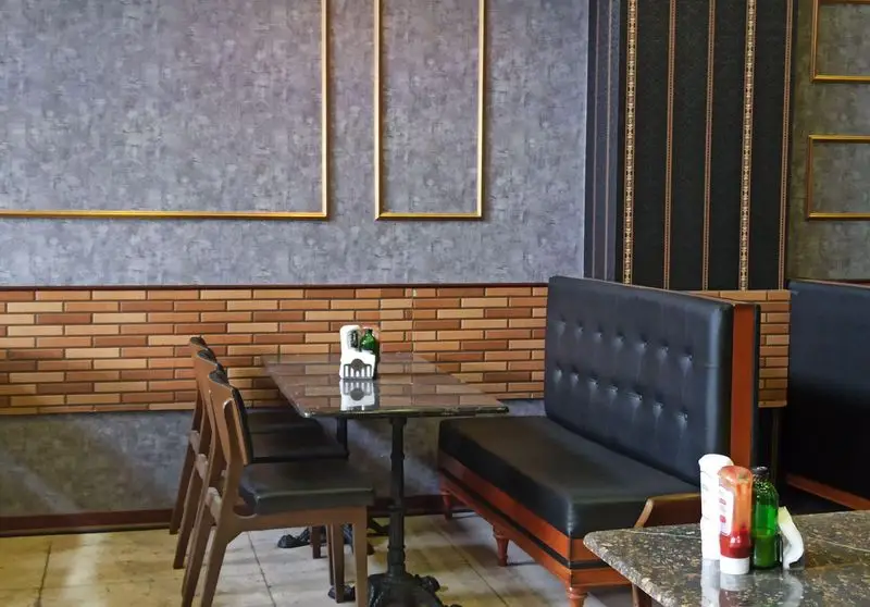 دکوراسیون داخلی شیک و مدرن فست فود گزینگ برگر، با میز و صندلی‌های راحت و کاناپه‌های چرمی، مکانی دلنشین برای سرو غذا.