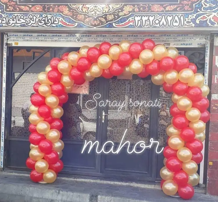 ورودی سرای سنتی ماهور با طاق بادکنکی قرمز و طلایی برای جشن. بالای درب، تابلوی فارسی "دارای تالار خانواده" و شماره تماس مشخص است.