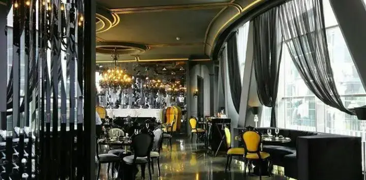 تصویری از فضای داخلی لوکس رستوران/کافه آوا سنتر با دکوراسیون شیک، مبلمان مشکی و طلایی، آینه‌ها و لوسترهای زیبا. مکانی ایده‌آل.