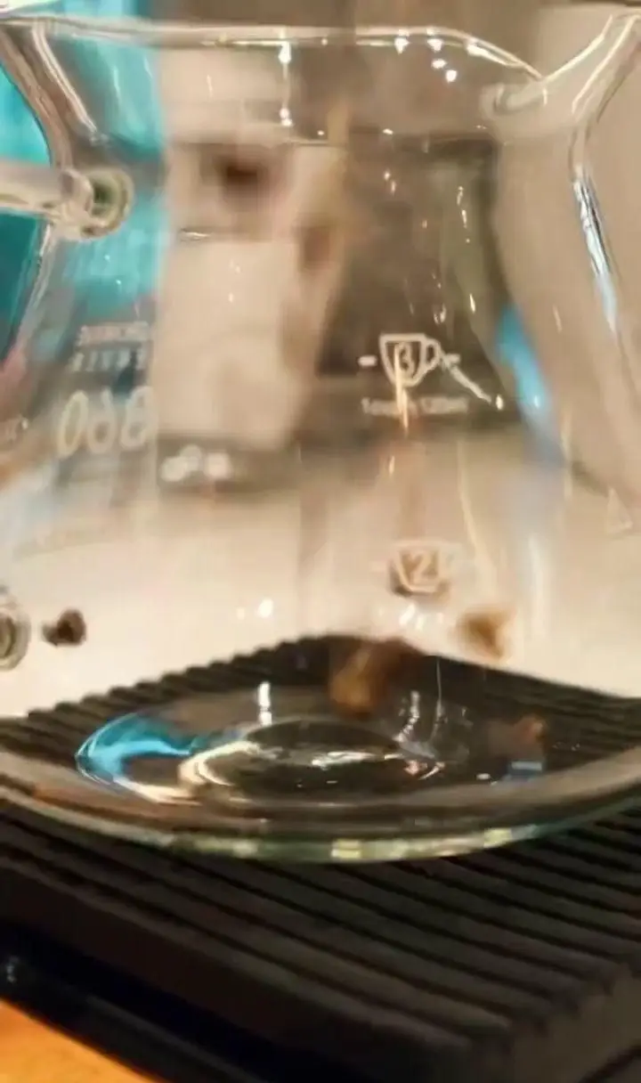 تصویری از دانه های قهوه معطر در قهوه ساز شیشه ای مدرن کافه لوما، نمایانگر کیفیت و تجربه خاص نوشیدن قهوه.