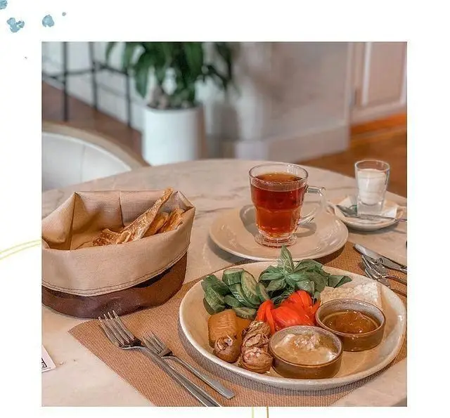 سفره صبحانه مفصل و لذیذ کافه لوما با چای گرم، نان تازه، پنیر، سبزیجات، مربا و لبنیات در فضایی دلنشین و آرام.