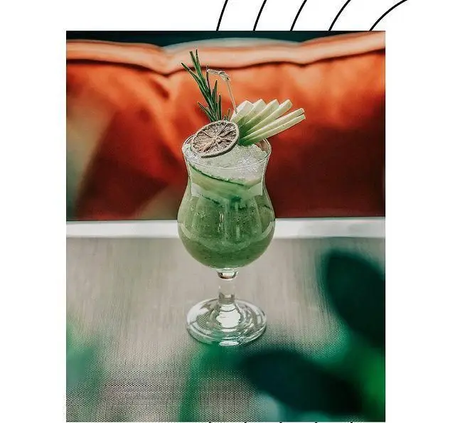 نوشیدنی سبز خنک و تازه کافه لوما با تزیین خیار، لیمو خشک و رزماری. تجربه‌ای دلپذیر در محیط آرام کافه لوما.