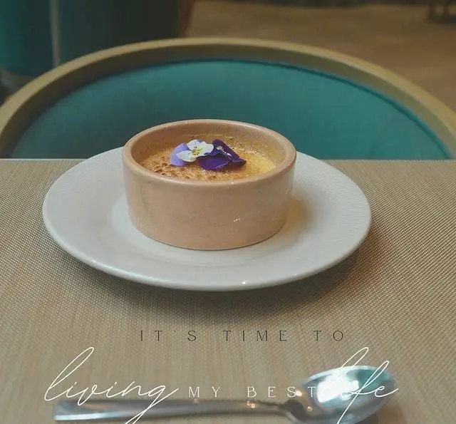 کرم بروله خوشمزه کافه لوما با تزیین گل‌های خوراکی، سرو شده در محیطی آرامش‌بخش و دلنشین. لذت دسر در کافه لوما.