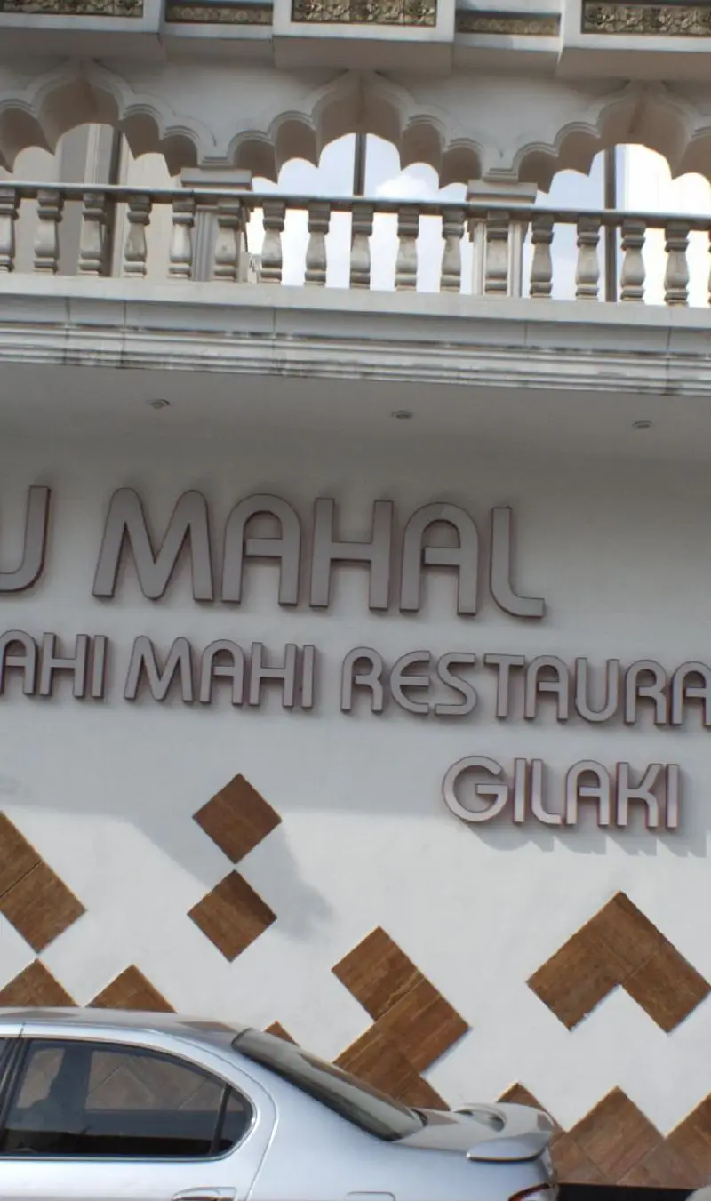 تصویر نمای خارجی رستوران تاج محل و رستوران ماهی ماهی، با تابلوی گیلکی و جزئیات معماری سنتی هندی و بالکن زیبای آن.