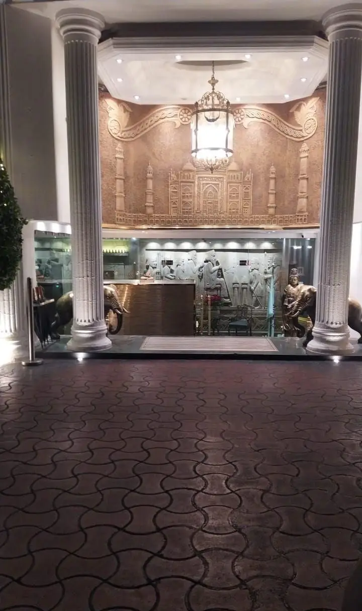 نمای بیرونی رستوران تاج محل در شب با دکوراسیون الهام گرفته از معماری هندی، شامل ستون‌های بلند، نقش برجسته تاج محل و مجسمه‌های فیل.