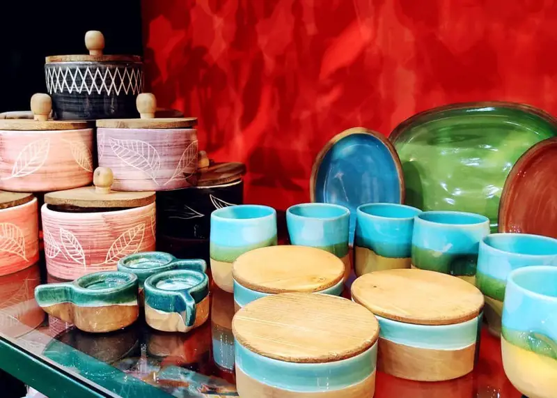 نمایشگاهی چشم‌نواز از صنایع دستی سرامیکی متنوع و رنگارنگ: کوزه‌های طرح‌دار با درب چوبی، ماگ و بشقاب، موجود در فروشگاه داربوک.