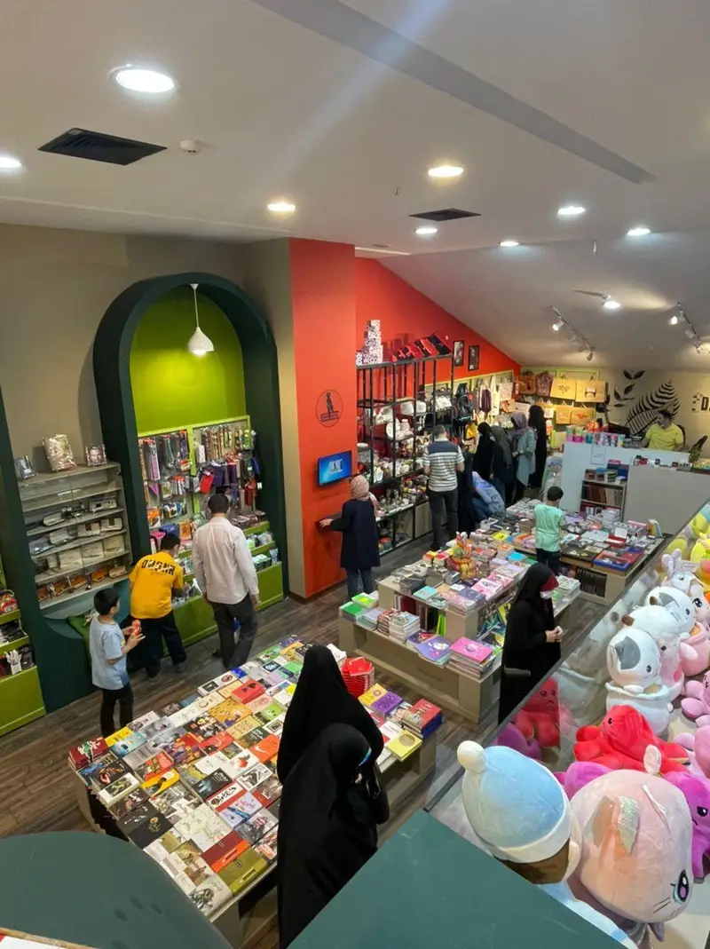 تصویر داخلی فروشگاه کتاب داربوک، محیطی شلوغ با مشتریانی که مشغول انتخاب و خرید انواع کتاب، نوشت‌افزار و اسباب‌بازی‌های متنوع هستند.