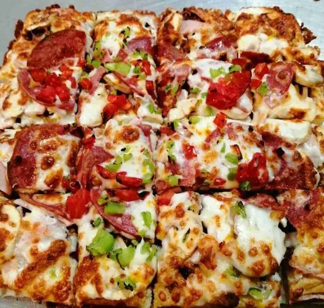 پیتزا اروند: سینی پیتزا لقمه‌ای مربع با پپرونی، فلفل دلمه‌ای و گوجه‌فرنگی تازه، پوشیده از پنیر طلایی و ذوب شده. پیتزایی خوشمزه و آماده سرو.