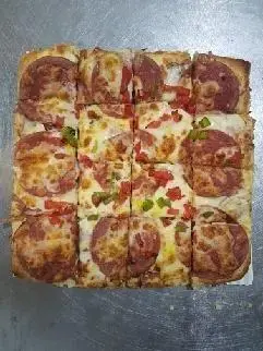 پیتزای مستطیلی بزرگ پپرونی تازه پخته شده با پنیر فراوان و فلفل‌های دلمه‌ای رنگی، برش‌خورده به ۱۶ تکه، محصول پیتزا اروند.