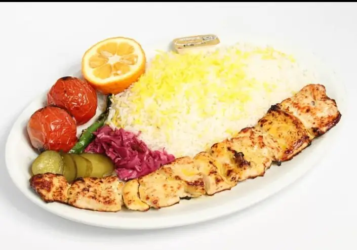 چلو جوجه کباب مخصوص رستوران معلم با تکه های مرغ گریل شده، برنج سفید زعفرانی، گوجه کبابی، نارنج، خیارشور و ترشی کلم.
