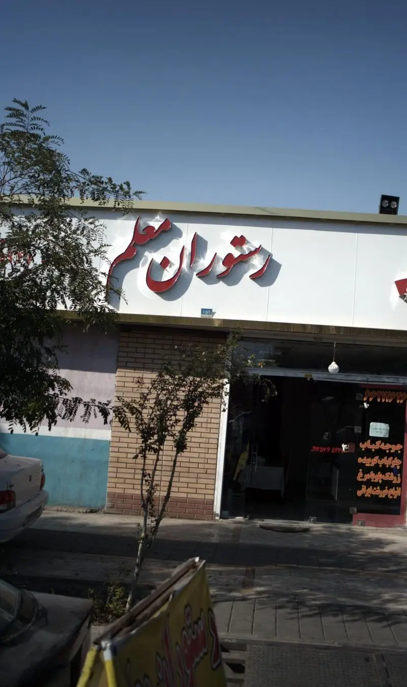 نمای بیرونی رستوران معلم با تابلوی مشخص، ارائه دهنده غذاهای اصیل ایرانی شامل جوجه کباب، چلو کباب کوبیده، زرشک پلو با مرغ و خورش‌های لذیذ.