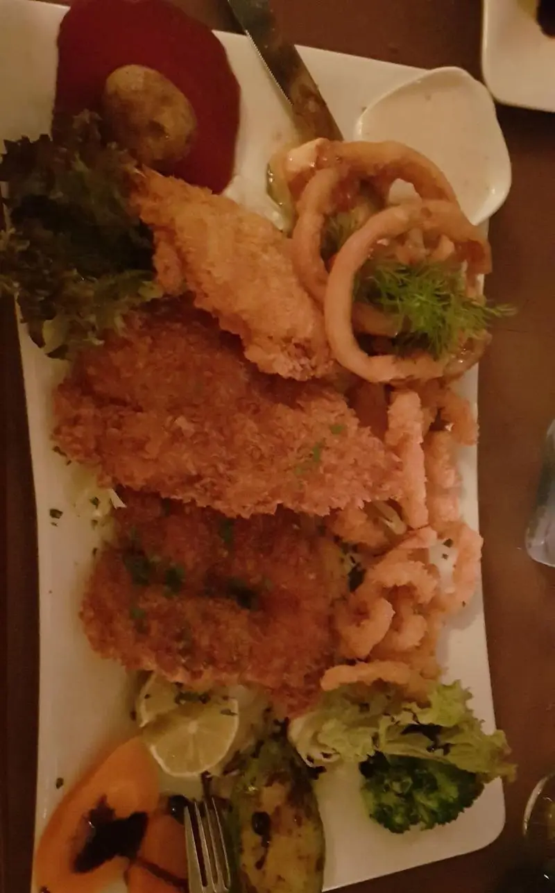 بشقاب میکس غذای دریایی سوخاری (ماهی، میگو، کالاماری) در رستوران ایتالیایی بلامونیکا همراه با سس تارتار، سالاد تازه و سبزیجات.