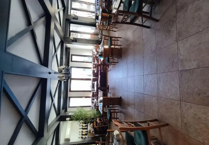 فضای داخلی رستوران ایتالیایی بلامونیکا با دکوراسیون چوبی، میز و صندلی‌های شیک، پنجره‌های بزرگ و محیطی دلنشین برای صرف غذا.