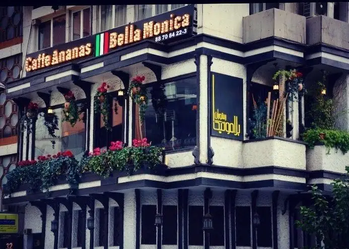 نمای بیرونی رستوران ایتالیایی و کافه بلامونیکا با طراحی زیبا، گل و گیاه، و تابلوی Caffe Ananas و Bella Monica.