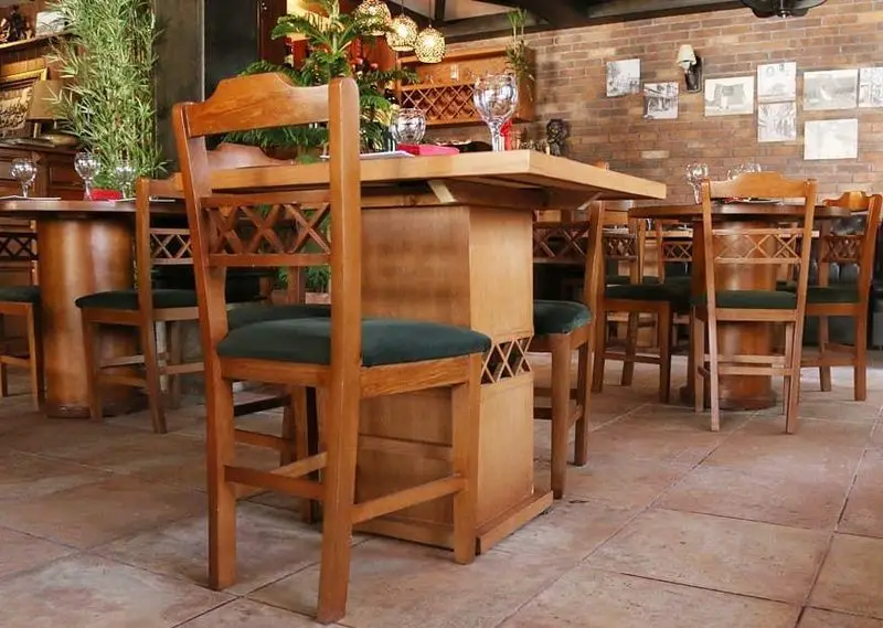 فضای داخلی دنج و شیک رستوران ایتالیایی بلامونیکا با میز و صندلی چوبی طرح‌دار، دیوار آجری و گیاهان تزئینی.