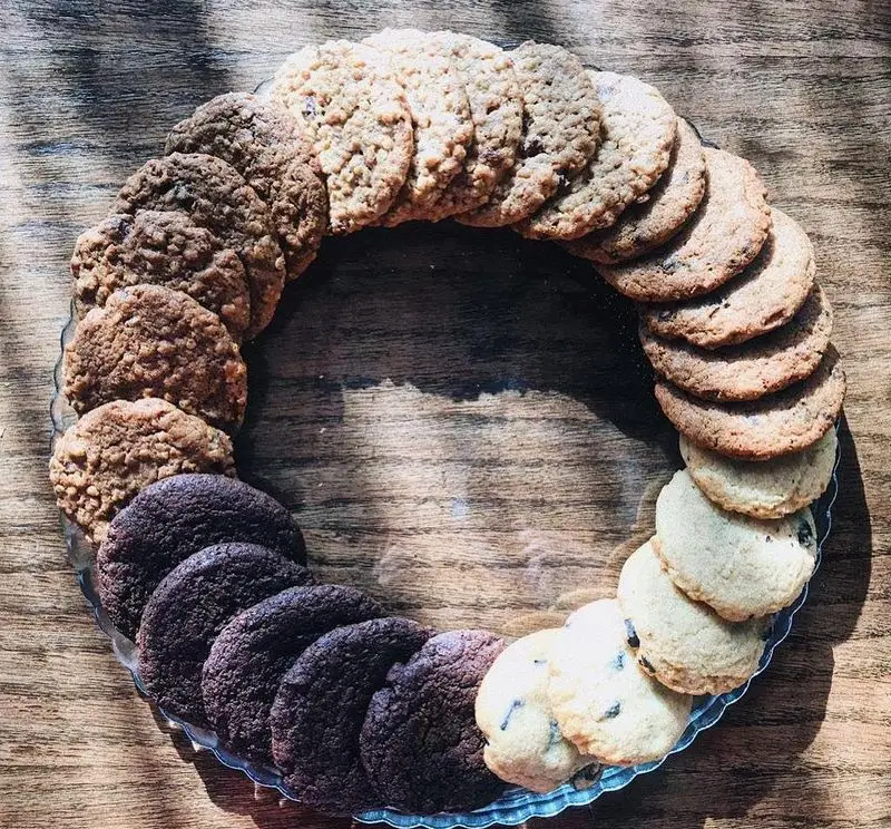 حلقه ای از انواع کوکی های خوشمزه کافه تایپ روی سینی شیشه‌ای. این کوکی‌ها با طعم‌های روشن، جو دوسر، دارچینی و شکلاتی به زیبایی چیده شده‌اند.