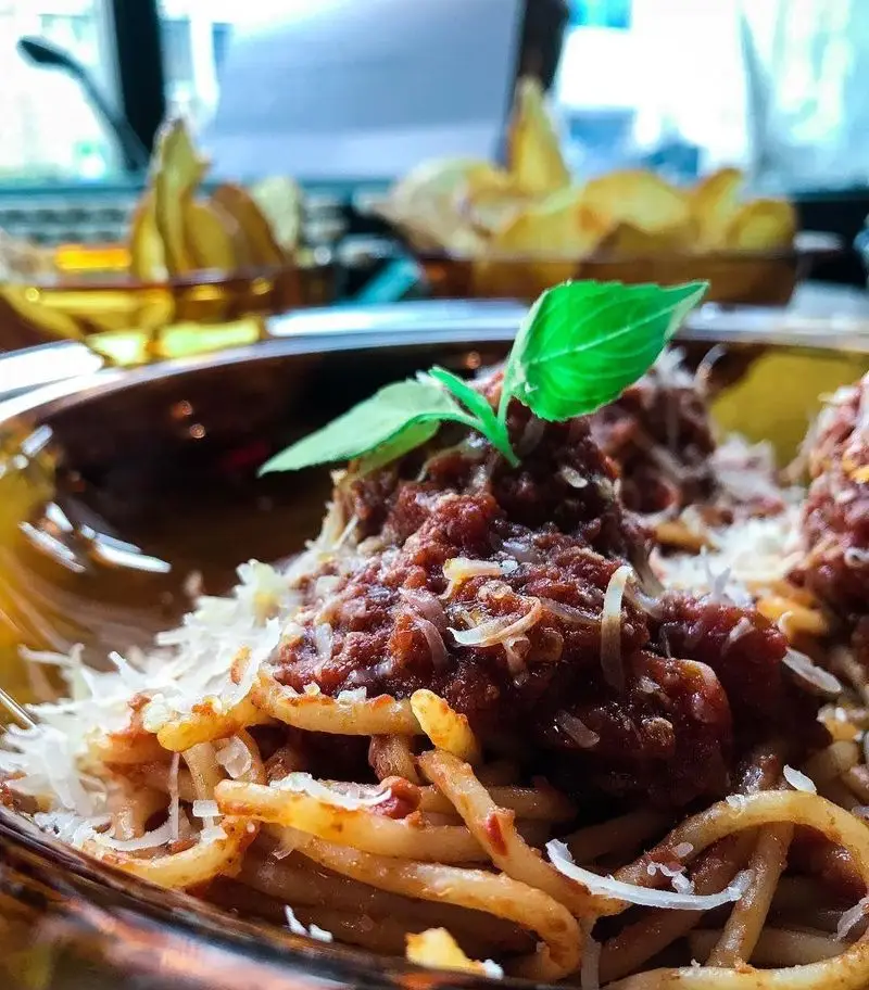پاستا اسپاگتی با سس بولونیز، پنیر پارمزان و برگ ریحان تازه در کافه تایپ. طعمی بی‌نظیر برای تجربه غذایی لذت‌بخش.