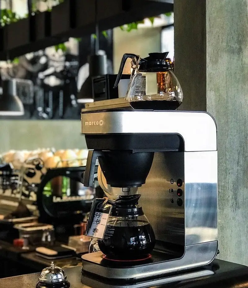 تصویر دستگاه قهوه ساز مارکو در کافه تایپ، قهوه فیلتری تازه دم شده را برای مشتریان آماده می‌کند. تجربه‌ای لذت‌بخش در کافه تایپ.