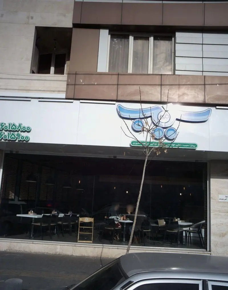 نمای بیرونی شعبه پیتزا سیب ۳۶۰، فست فود محبوب با تابلوی درخشان و ورودی شیشه‌ای. فضای داخلی مدرن و چیدمان میز و صندلی‌ها پیداست.