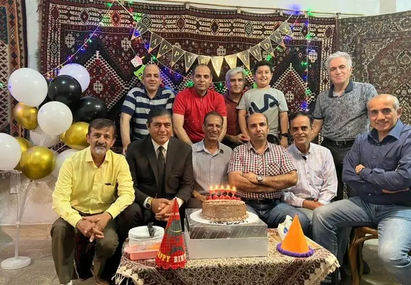 جمعی از دوستان در جشن تولدی صمیمی، با پس‌زمینه فرش‌های زیبای ایرانی که دکوراسیون خاص کافه فرش را نشان می‌دهد.