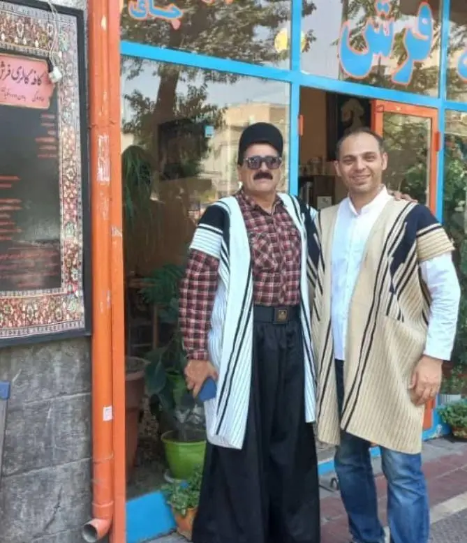 تصویری از دو مرد خوشرو در مقابل کافه فرش، مکانی منحصر به فرد که قالی اصیل ایرانی را با عطر دلپذیر قهوه ترکیب می‌کند.