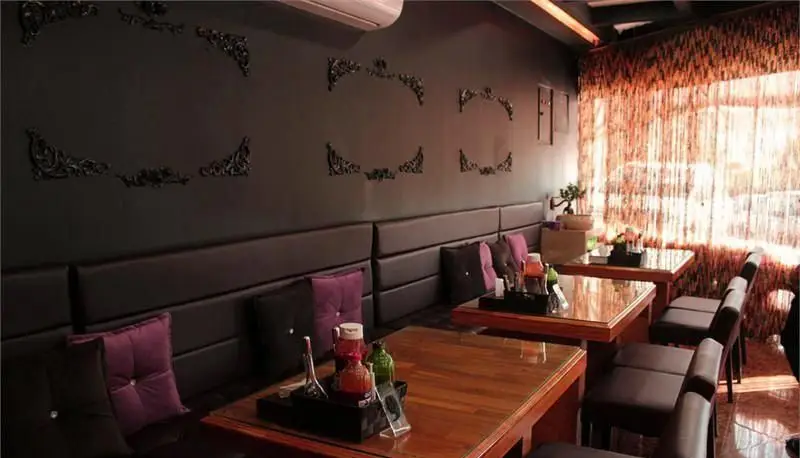 دکوراسیون داخلی شیک و مدرن فست فود ویچنزا با نیمکت‌های راحتی، میزهای چوبی و دیوارهای تیره با طرح‌های خاص.