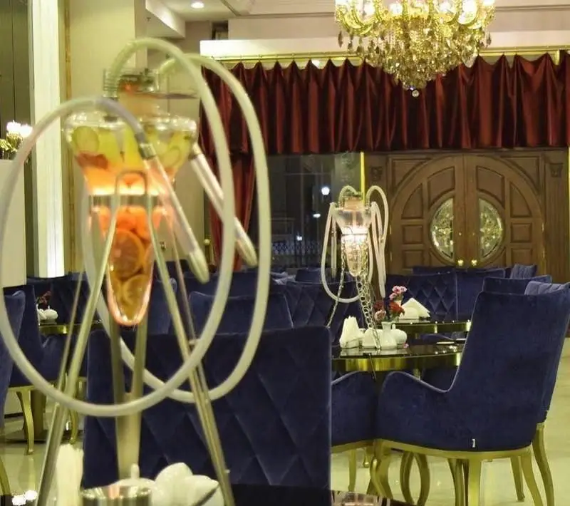 فضای داخلی لوکس رستوران فرنگی حافظ با صندلی‌های مخمل آبی، میزهای شیک و قلیان‌های میوه‌ای مجلل برای مشتریان.