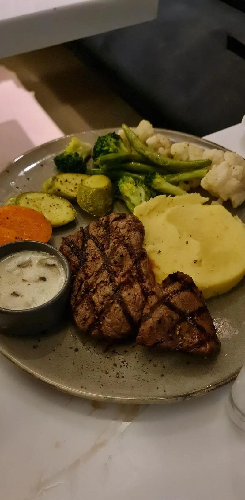 تصویر یک بشقاب استیک گریل‌شده آبدار، همراه با پوره سیب‌زمینی، سس قارچ و سبزیجات متنوع در رستوران ایتالیایی بونو ظفر.