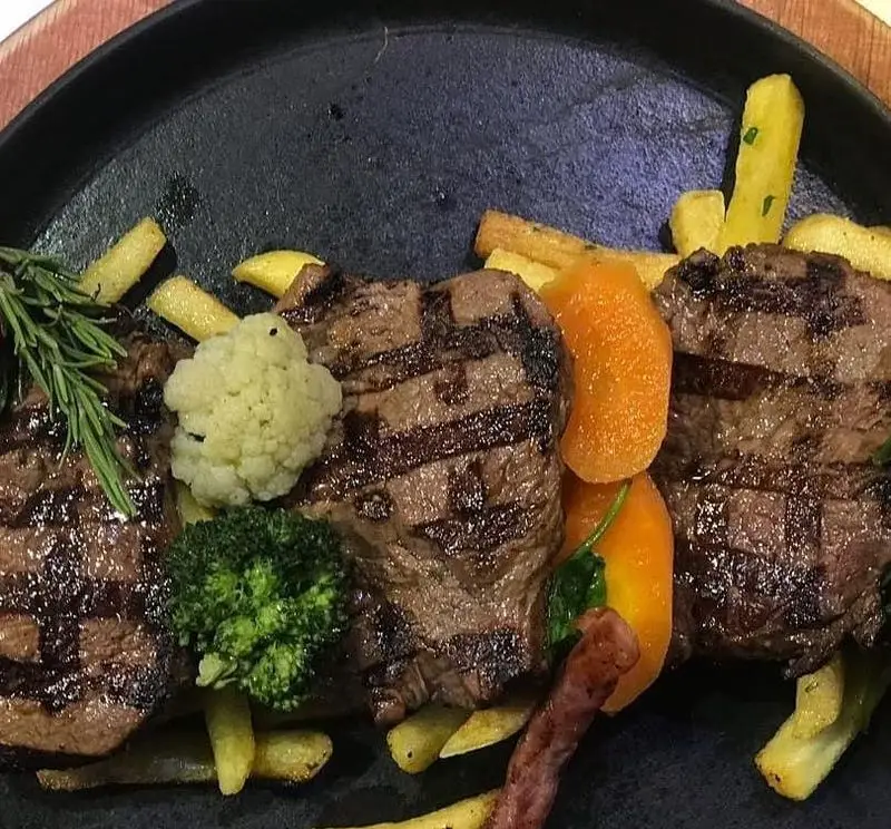 استیک گریل شده آبدار با دورچین سیب زمینی سرخ کرده، کلم بروکلی، گل کلم و هویج، غذایی لذیذ در رستوران ایتالیایی بونو ظفر.