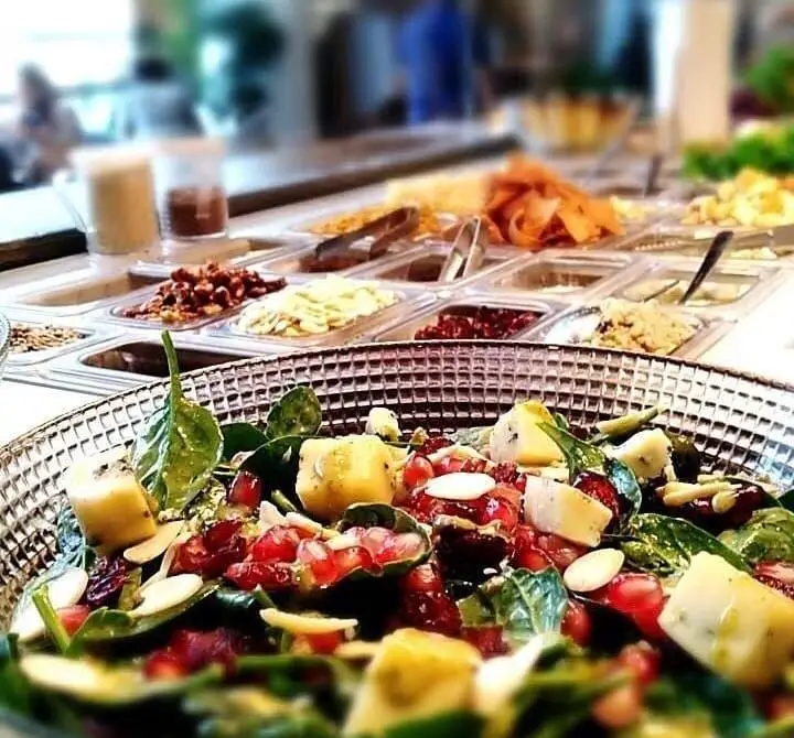 نمایی نزدیک از سالاد تازه و پرانرژی رستوران ایتالیایی بونو ظفر با اسفناج، انار، پنیر و بادام، ایده‌آل برای یک وعده سالم.