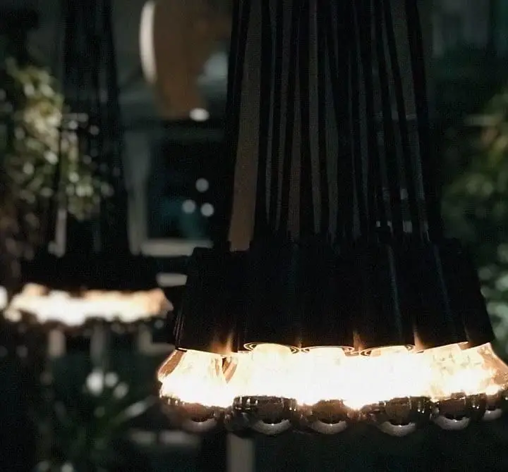 لوسترهای منحصر به فرد با لامپ‌های متعدد و نور گرم در دکوراسیون داخلی رستوران ایتالیایی بونو ظفر، فضایی دنج و دلپذیر.