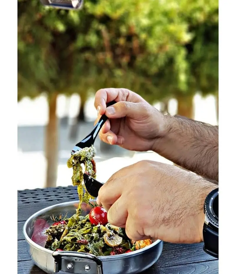 شخصی در حال میل کردن پاستا سبز خوشمزه در رستوران ایتالیایی بونو ظفر. تجربه عالی غذای ایتالیایی در فضای باز. پاستاهای درجه یک ظفر.