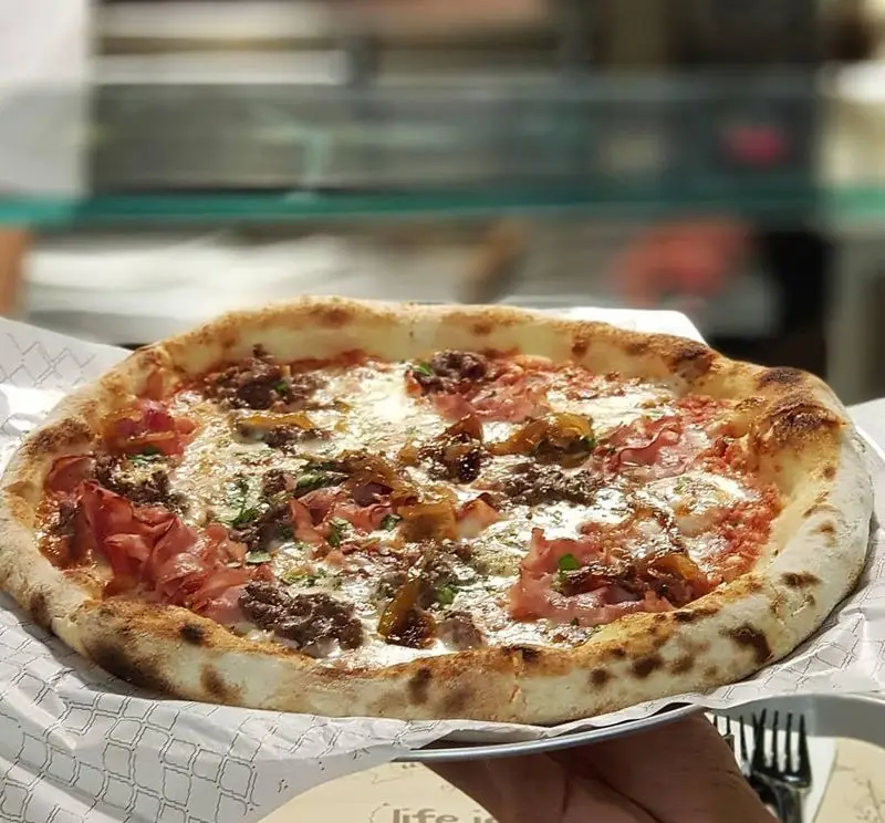 پیتزای ایتالیایی لذیذ با خمیر برشته، پنیر موزارلا، ژامبون، گوشت و پیاز کاراملی در رستوران بونو ظفر تهران.