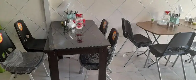 محیط داخلی طباخی قوچ سفید: میز و صندلی‌های مرتب و تمیز با کاور پلاستیکی، آماده سرو غذاهای لذیذ و پذیرایی از مشتریان.