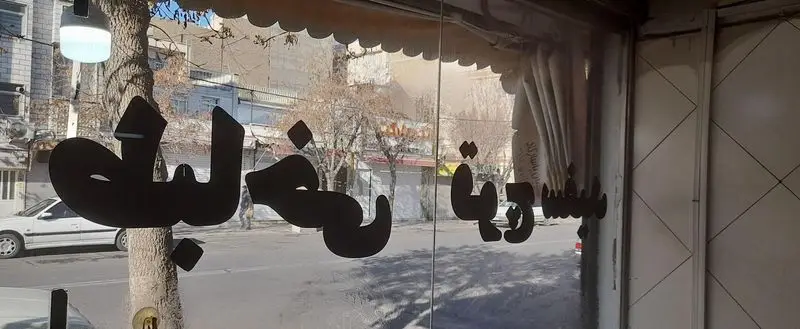 تصویر نمای بیرونی طباخی قوچ سفید، رستوران سنتی کله پاچه و سیرابی. نام "طباخی قوچ سفید" روی شیشه مغازه در خیابان.