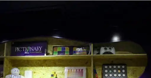 قفسه بازی‌های فکری (Pictionary)، کنسول بازی ایکس‌باکس و سرگرمی‌های متنوع در محیط دنج رستوران فرنگی پیچ.