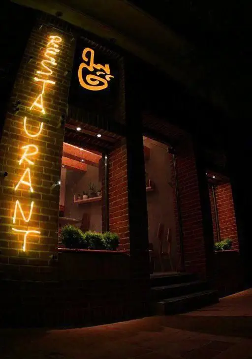 نمای بیرونی شیک و جذاب رستوران فرنگی پیچ در شب، با تابلوی نئون "RESTAURANT" و لوگوی درخشان "پیچ" روی بنای آجری و نورپردازی گرم.