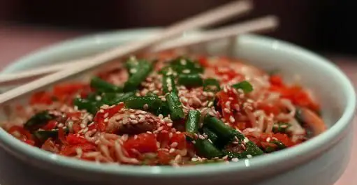 کاسه‌ای پر از نودل داغ و خوشمزه با سبزیجات تازه، فلفل دلمه‌ای، لوبیا سبز و کنجد، همراه چاپستیک در رستوران فرنگی پیچ.