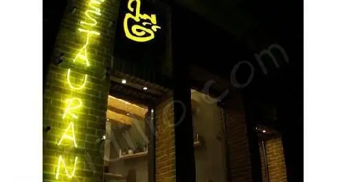 رستوران فرنگی پیچ: نمای بیرونی در شب با تابلوی نئون زرد رنگ "RESTAURAN" و لوگوی منحصر به فرد، محیطی گرم و دعوت کننده.