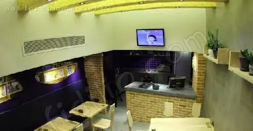 تصویری از فضای داخلی شیک و مدرن رستوران فرنگی پیچ با میز و صندلی‌های چوبی، کانتر آشپزخانه و تزئینات زیبا.