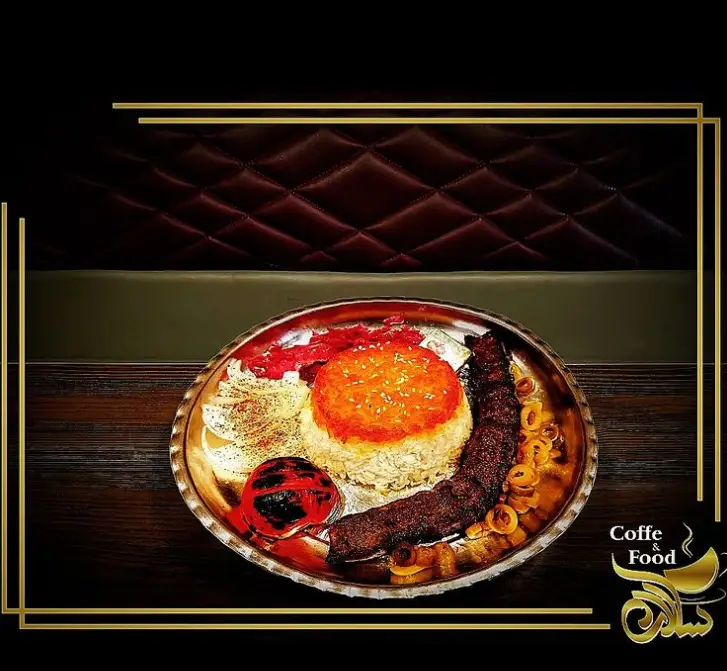 کباب لذیذ با برنج زعفرانی و گوجه کبابی در بشقاب سنتی، غذای اصیل و خوشمزه از کافه رستوران سالار برای شما.